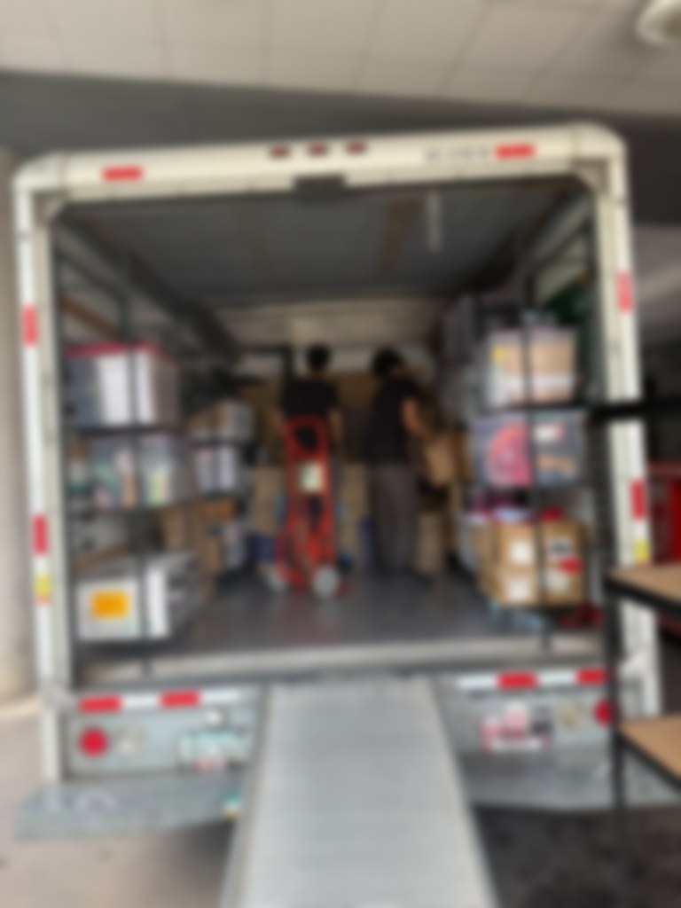 Two crew members loading boxes inside a packed moving truck