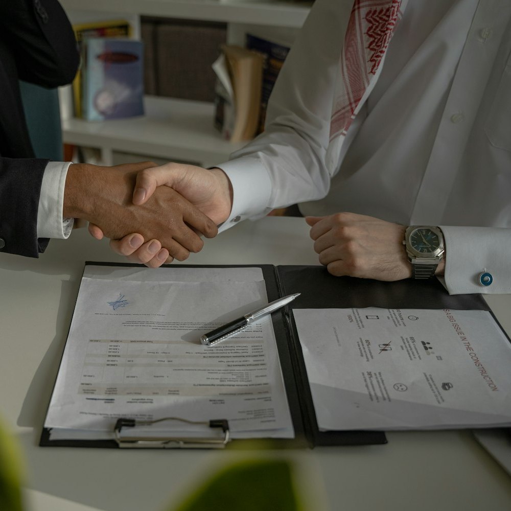 Two people shaking hands over a signed written quote on a clipboard